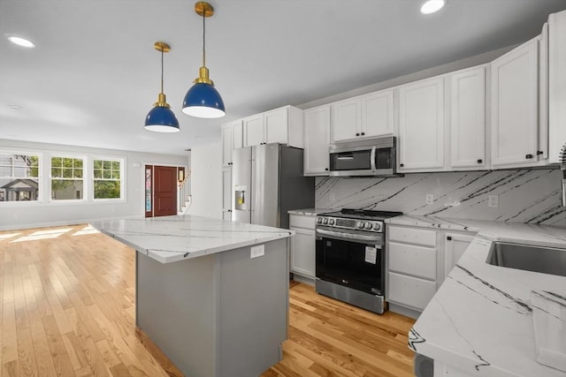 kitchen with white cabinetry, light stone countertops, hanging light fixtures, stainless steel appliances, and backsplash