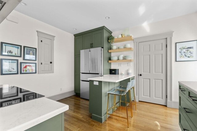 149-151 Pleasant St, Watertown, MA 02472 - kitchen featuring green cabinetry, freestanding refrigerator, light wood-type flooring, light countertops, and a kitchen bar
