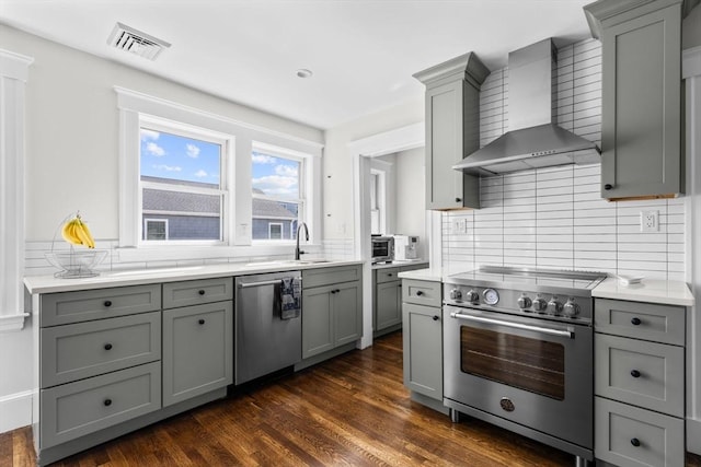 149-151 Pleasant St, Watertown, MA 02472 - kitchen with stainless steel appliances, gray cabinets, wall chimney range hood, backsplash, and light countertops