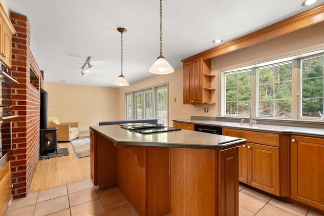 kitchen featuring black appliances, a sink, light tile patterned flooring, and a kitchen island