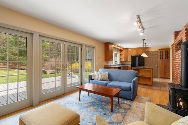 living area featuring rail lighting, french doors, a wood stove, and light wood-type flooring