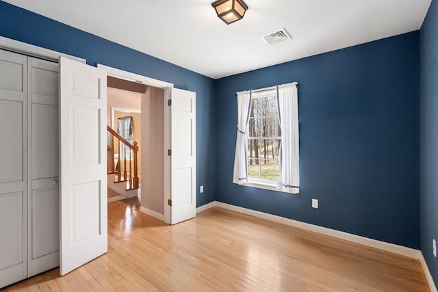 unfurnished bedroom featuring baseboards, light wood finished floors, visible vents, and a closet