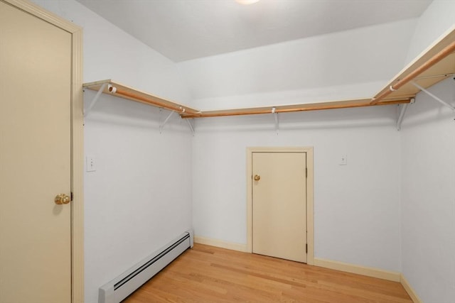 spacious closet with a baseboard heating unit and light wood finished floors