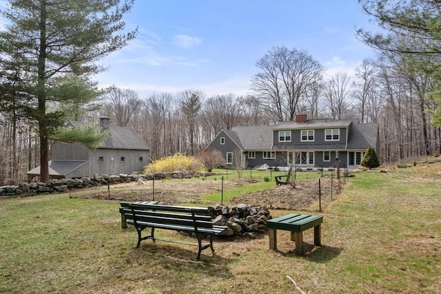 back of property featuring an outbuilding, a yard, and a chimney