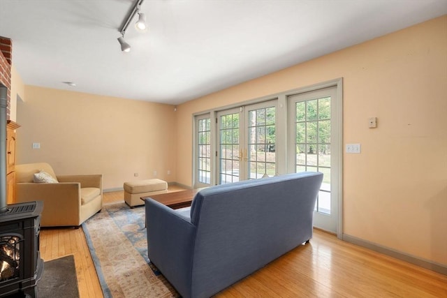 living area with baseboards, rail lighting, light wood finished floors, and a wood stove
