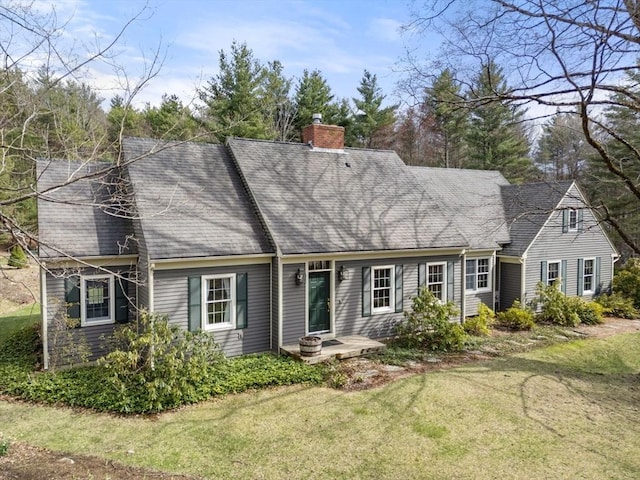 view of front of home with a chimney, roof with shingles, and a front lawn
