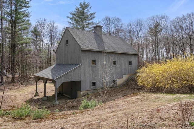 view of home's exterior featuring a chimney and roof with shingles