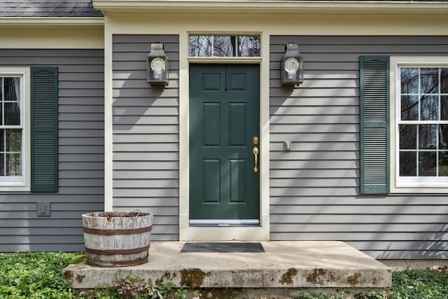 doorway to property featuring roof with shingles