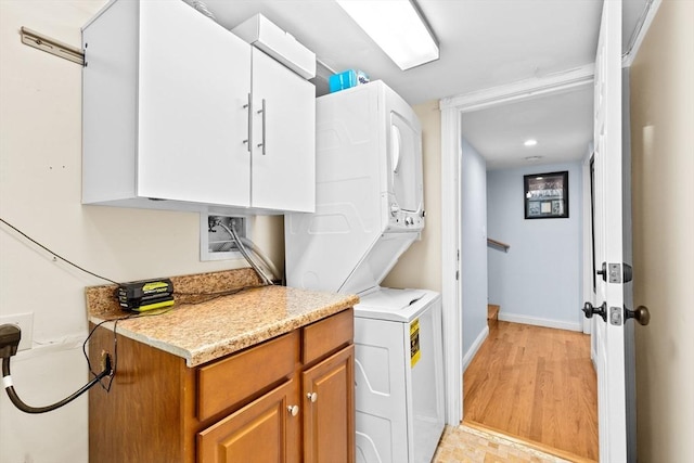 13 Emmet St Unit 1, Boston, MA 02127 - laundry area featuring estacked washer and dryer, cabinet space, baseboards, and light wood-style floors