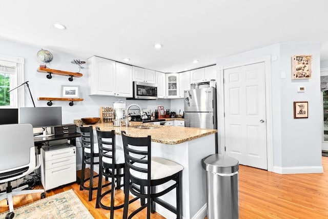 13 Emmet St Unit 1, Boston, MA 02127 - kitchen with appliances with stainless steel finishes, a peninsula, glass insert cabinets, white cabinets, and recessed lighting