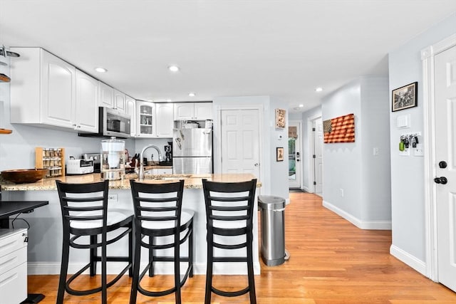 13 Emmet St Unit 1, Boston, MA 02127 - kitchen with appliances with stainless steel finishes, a peninsula, white cabinetry, recessed lighting, and a kitchen breakfast bar