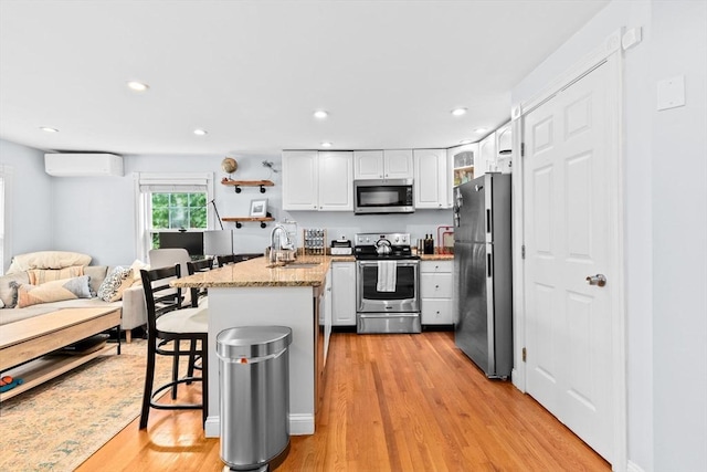 13 Emmet St Unit 1, Boston, MA 02127 - kitchen with appliances with stainless steel finishes, a wall unit AC, a sink, a peninsula, and white cabinets