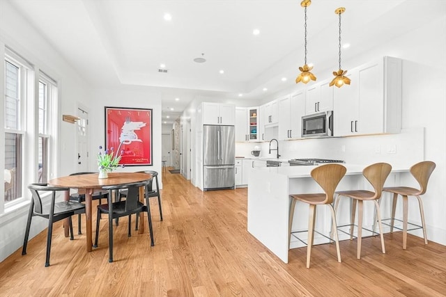239 Lexington St Unit 2, Boston, MA 02128 - kitchen with stainless steel appliances, light countertops, light wood-type flooring, a kitchen breakfast bar, and a peninsula