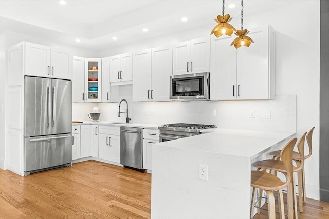 239 Lexington St Unit 2, Boston, MA 02128 - kitchen with appliances with stainless steel finishes, a peninsula, recessed lighting, a kitchen bar, and glass insert cabinets