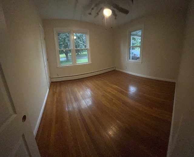 empty room with a baseboard heating unit, ceiling fan, dark hardwood / wood-style floors, and a healthy amount of sunlight