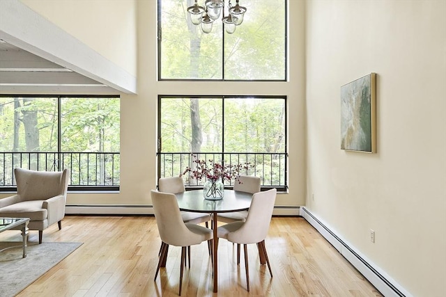 993 Massachusetts Ave Unit 127, Arlington, MA 02476 - dining space with a baseboard heating unit, a towering ceiling, a chandelier, and light wood finished floors