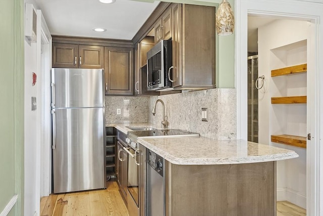 kitchen featuring backsplash, dark brown cabinets, light wood-style flooring, recessed lighting, and stainless steel appliances