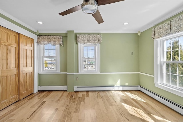 interior space with ornamental molding, a baseboard heating unit, and wood finished floors