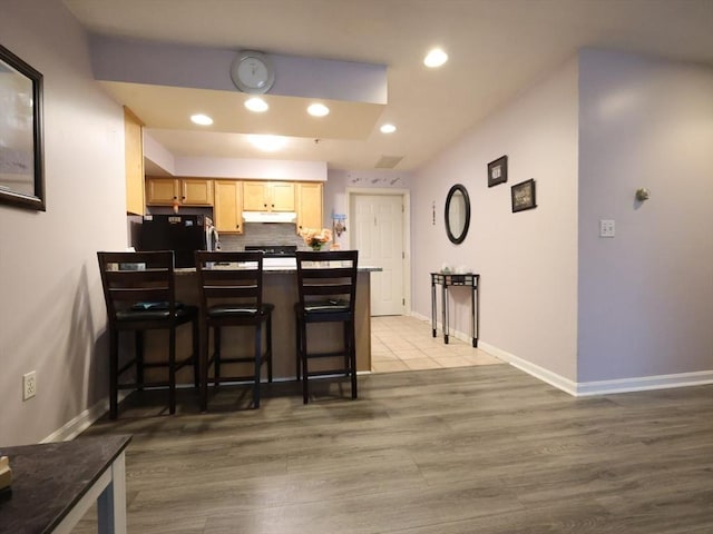 234 Water St Unit 101, Wakefield, MA 01880 - kitchen with fridge, under cabinet range hood, a peninsula, a breakfast bar area, and light brown cabinets