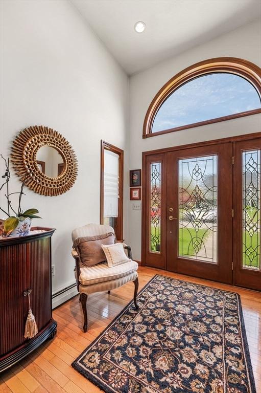 entrance foyer featuring light wood-style floors, a baseboard heating unit, a high ceiling, and recessed lighting
