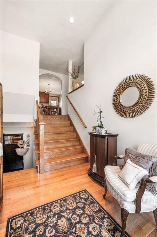 stairway featuring wood finished floors, arched walkways, and recessed lighting