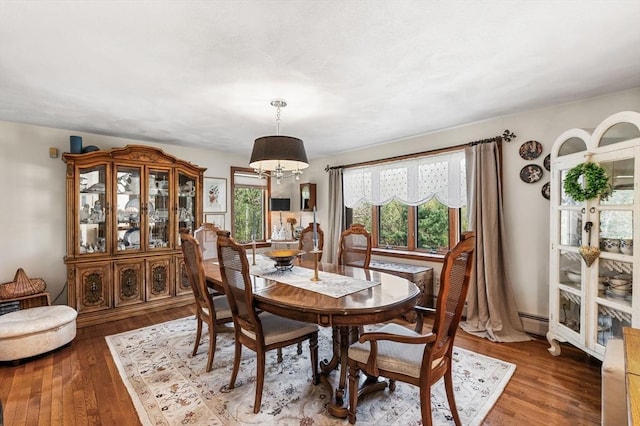 dining room featuring a chandelier, wood-type flooring, and a baseboard heating unit