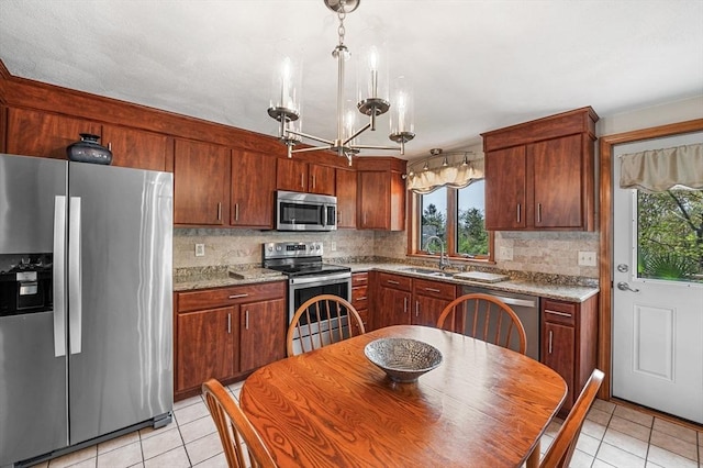 kitchen with appliances with stainless steel finishes, a sink, light tile patterned flooring, backsplash, and a chandelier