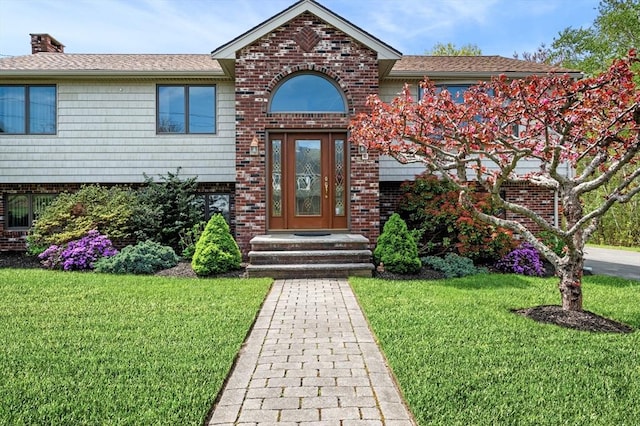 view of front of property with brick siding, a front yard, and a chimney