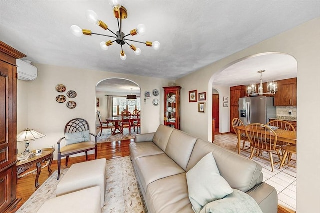 living area featuring a chandelier, arched walkways, an AC wall unit, and light tile patterned flooring