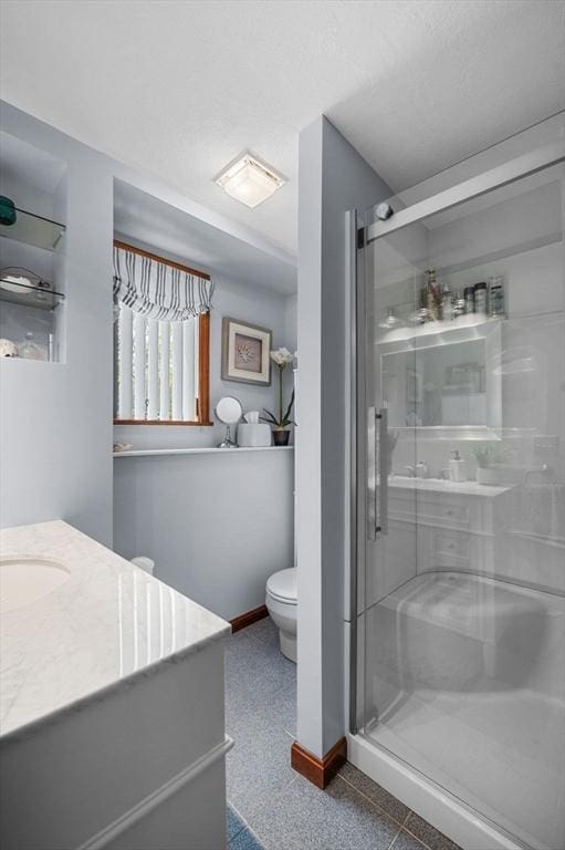 bathroom featuring a shower stall, baseboards, toilet, and vanity