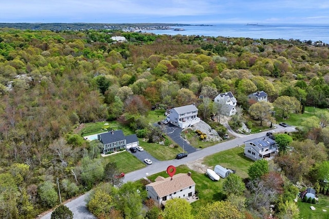 view of property location featuring a forest and a nearby body of water