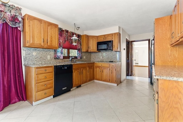 kitchen with brown cabinets, light stone countertops, a sink, decorative backsplash, and black appliances