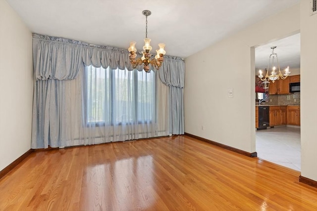 unfurnished dining area featuring light wood-type flooring, baseboards, and a chandelier