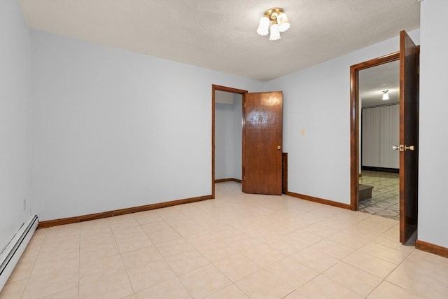 spare room featuring baseboards, a baseboard radiator, and a textured ceiling