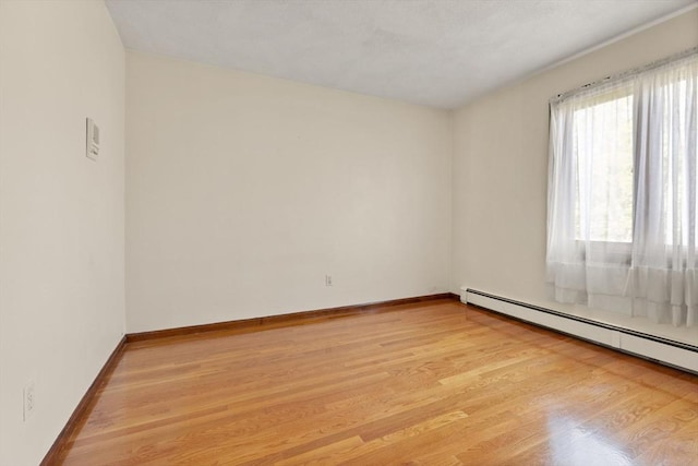 unfurnished room featuring light wood-type flooring, baseboards, and baseboard heating