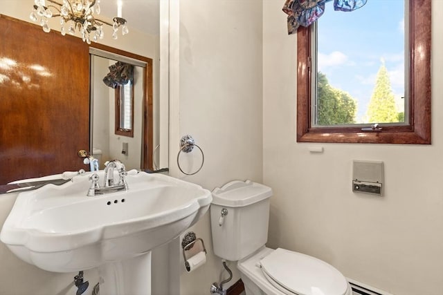 half bath with a baseboard heating unit, toilet, an inviting chandelier, and a sink
