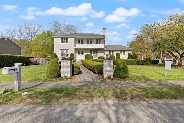 view of front of property with fence, a chimney, a front yard, and a balcony