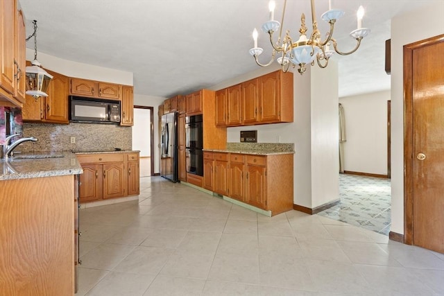 kitchen featuring black appliances, brown cabinets, a sink, backsplash, and a notable chandelier