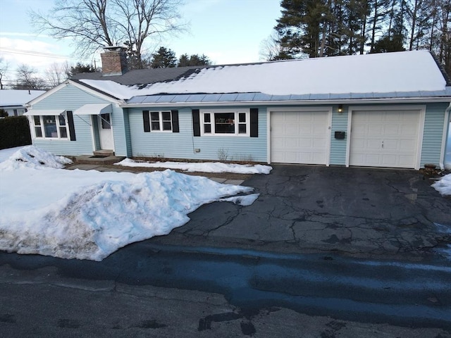 ranch-style home with a garage, driveway, and a chimney