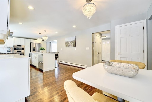 interior space with white cabinetry, hanging light fixtures, a baseboard heating unit, a center island, and an inviting chandelier