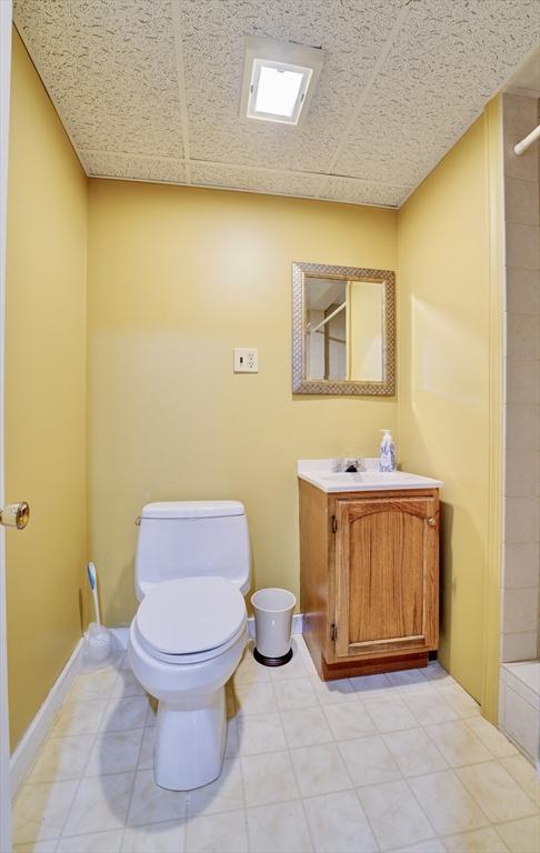 bathroom featuring vanity, a paneled ceiling, tile patterned floors, and toilet