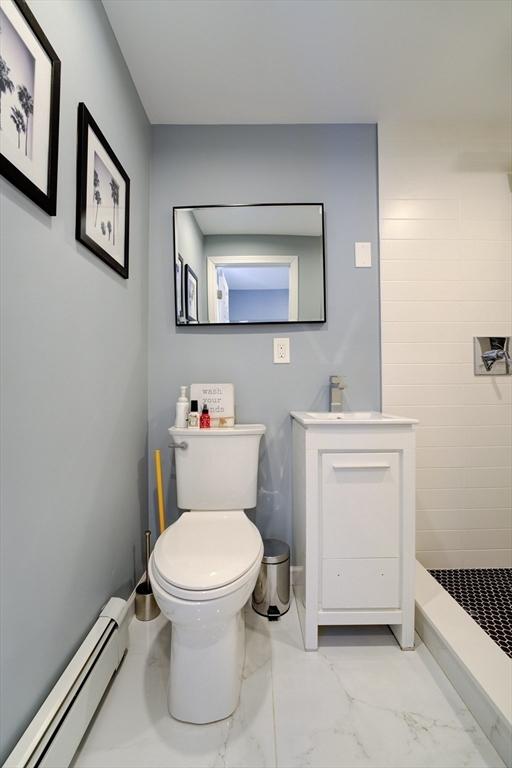 bathroom with a baseboard radiator, toilet, sink, and a shower