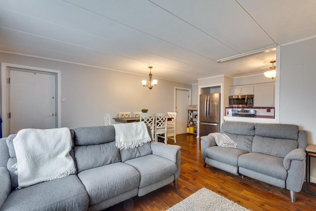 living room featuring dark wood-type flooring, a notable chandelier, and crown molding