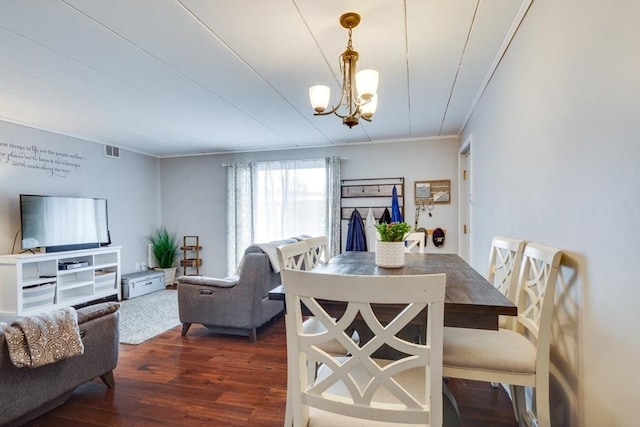 dining room with crown molding, visible vents, dark wood-type flooring, and a notable chandelier