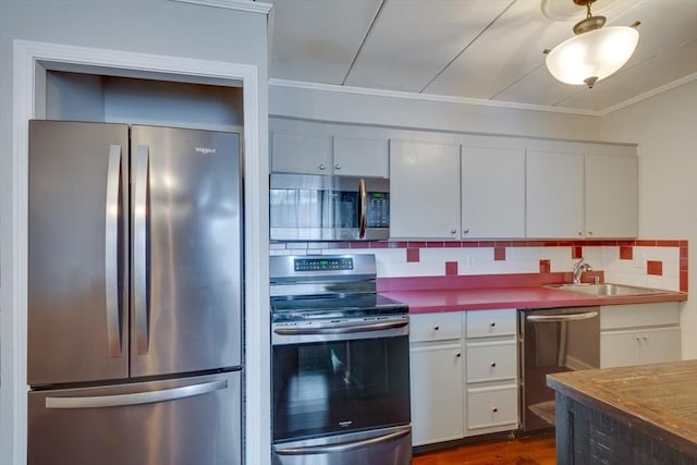 kitchen featuring appliances with stainless steel finishes, backsplash, a sink, and white cabinetry