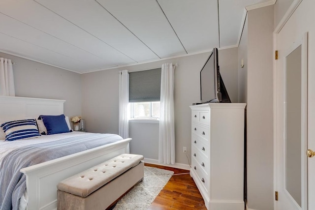 bedroom featuring ornamental molding, wood finished floors, and baseboards