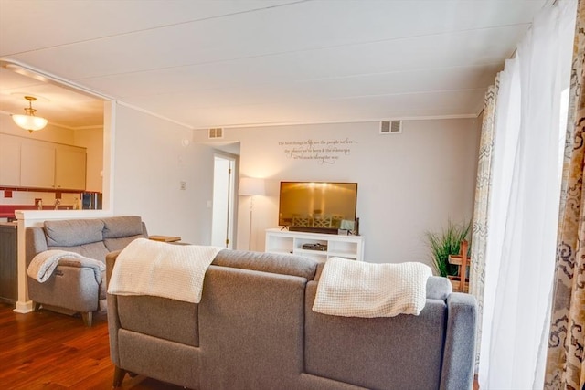 living room with wood finished floors, visible vents, and crown molding