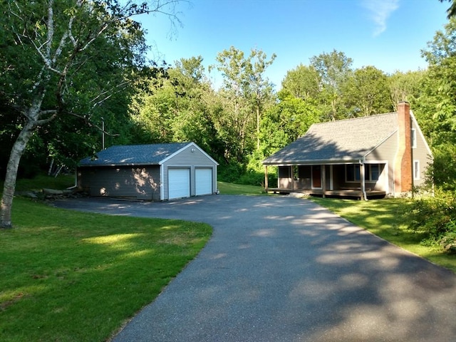 view of front facade with a front yard, a porch, a garage, and an outbuilding