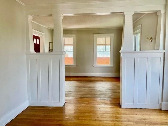 interior space with decorative columns, crown molding, and light hardwood / wood-style floors