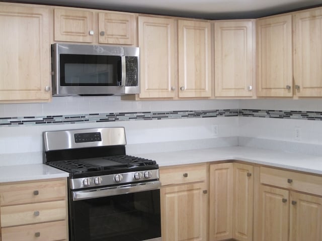 kitchen featuring appliances with stainless steel finishes, light brown cabinets, and backsplash